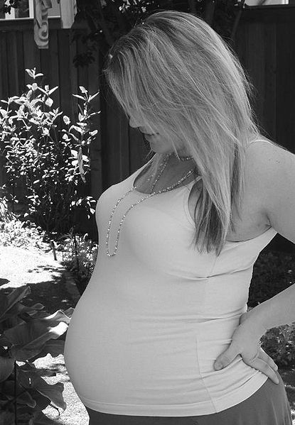 A heavily pregnant woman. Notice the arch in her lower back. At this time in pregnancy she will be experiencing back strain from the heavy weight she is carrying.