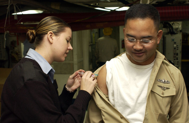 Hospital Corpsman 3rd Class Tiffany Long administers the influenza vaccination to a crew member aboard USS Kitty Hawk
