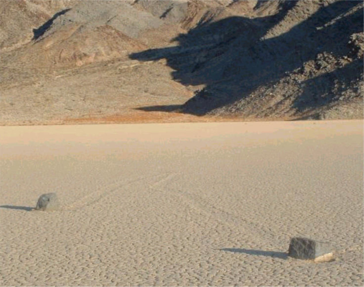 Picture of two rocks on Racetrack Playa in Death Valley. Notice the mysterious groves leading away from the stones.