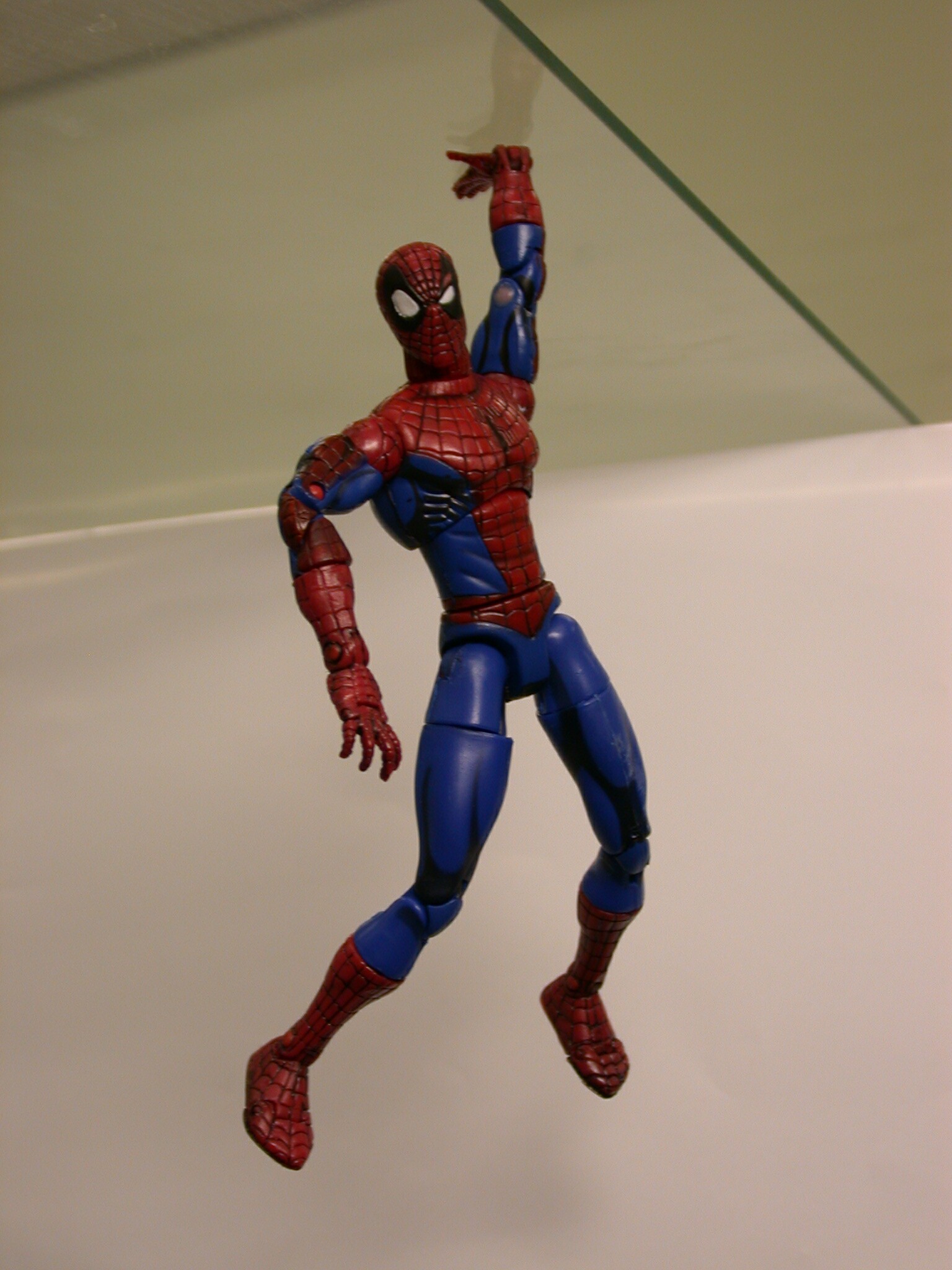 Spiderman toy hanging from a glass plate, attached using the tape with a contact area of approximately 0.5cm2 with a carry load of >100g. This toy has been attached to several surfaces before this photo was taken.