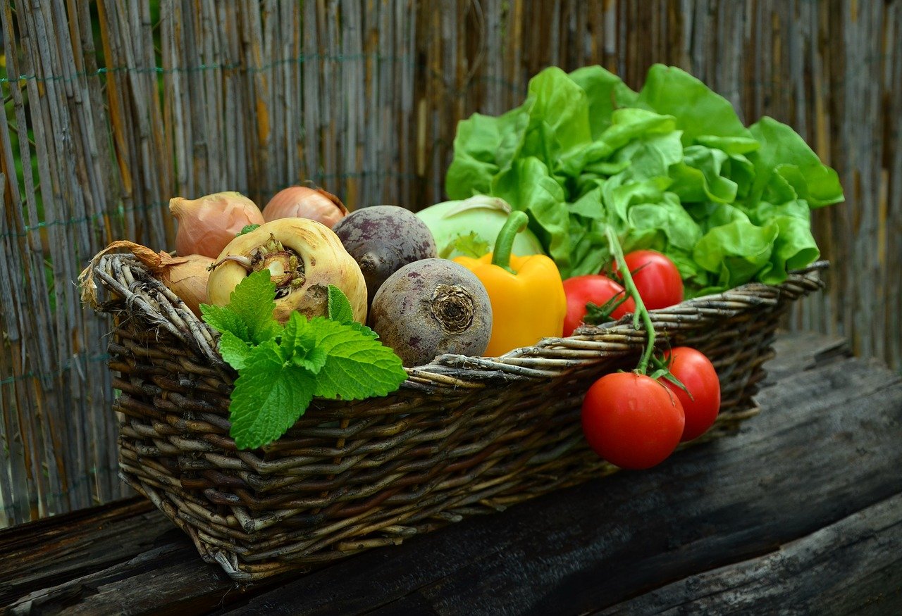 A wicker basket filled with an assortment of different vegetables