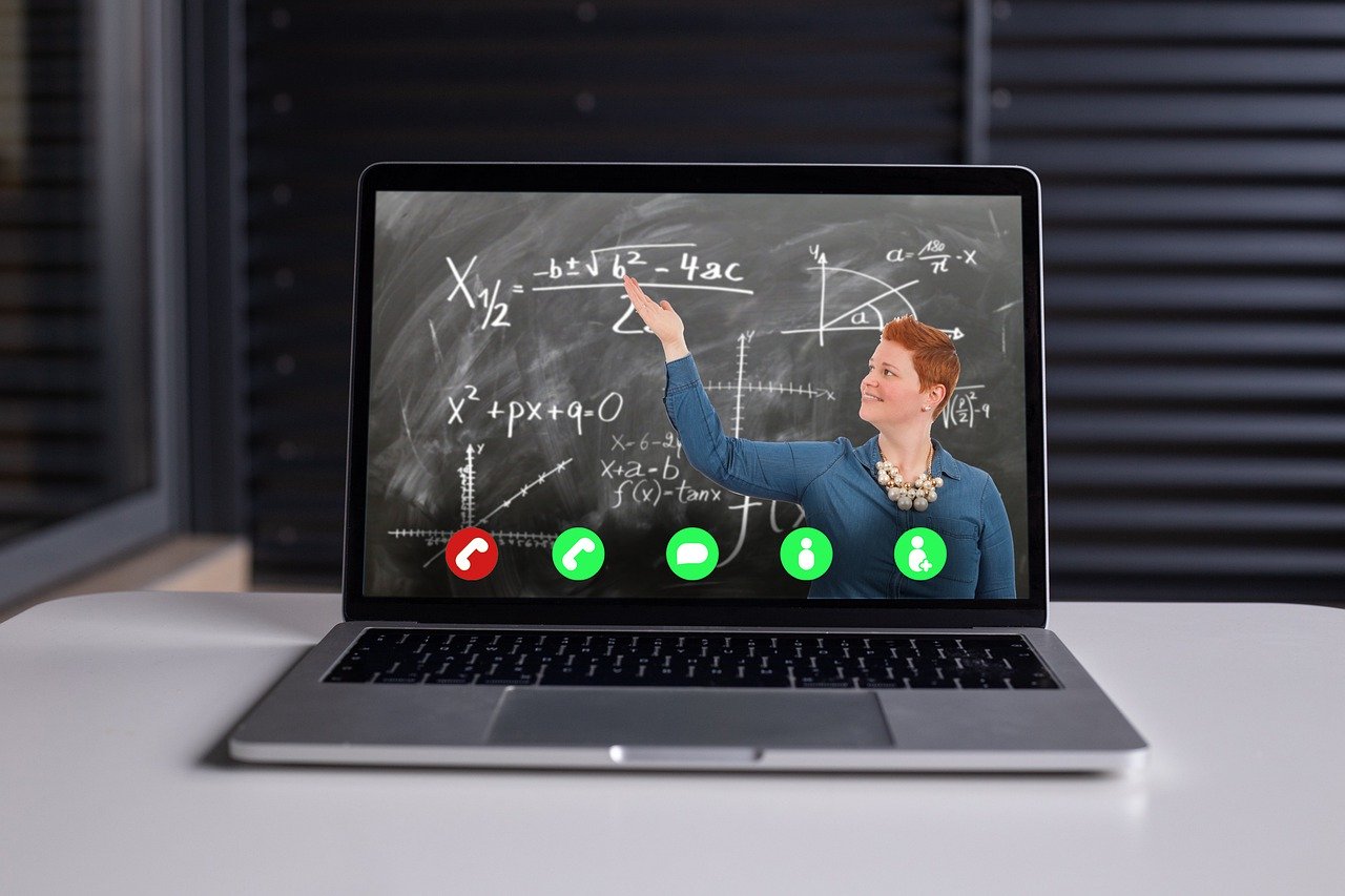 image of teacher next to blackboard, via video call