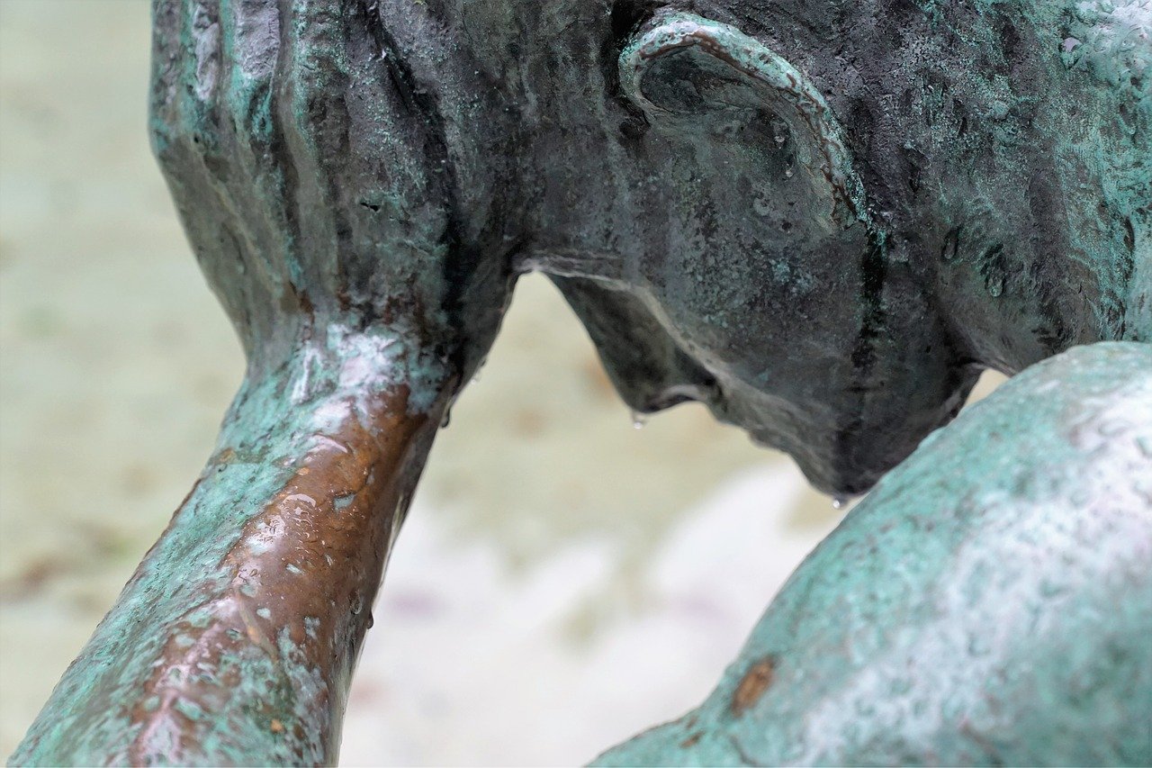 a stone statue of a man with his head in his hands