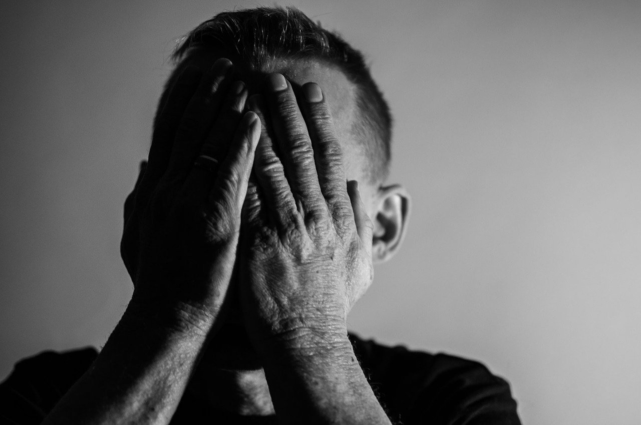 A man covering his hands with his face.