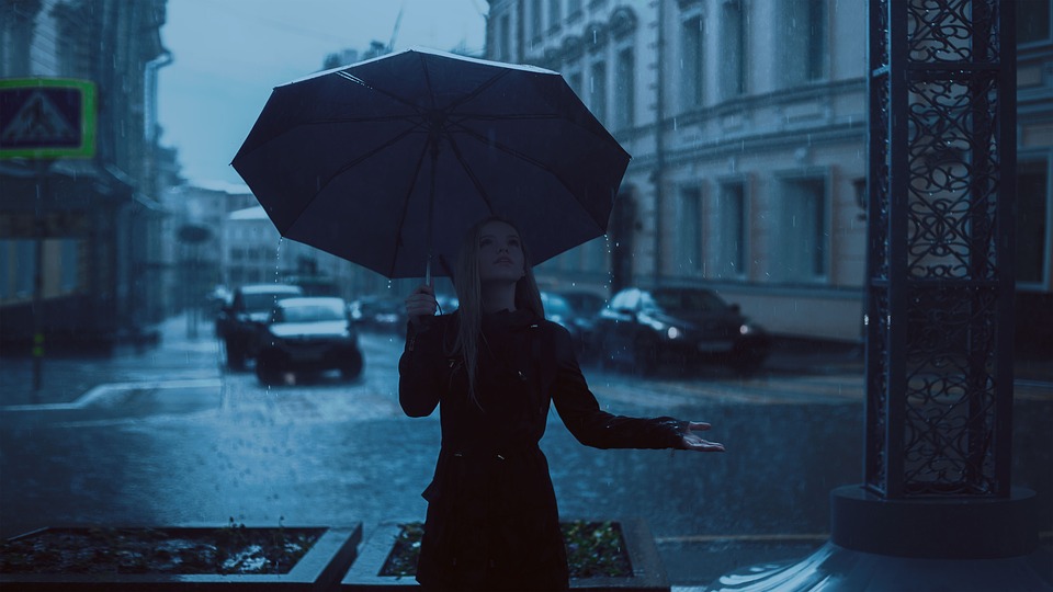 A girl holding an umbrella checks if it is still raining