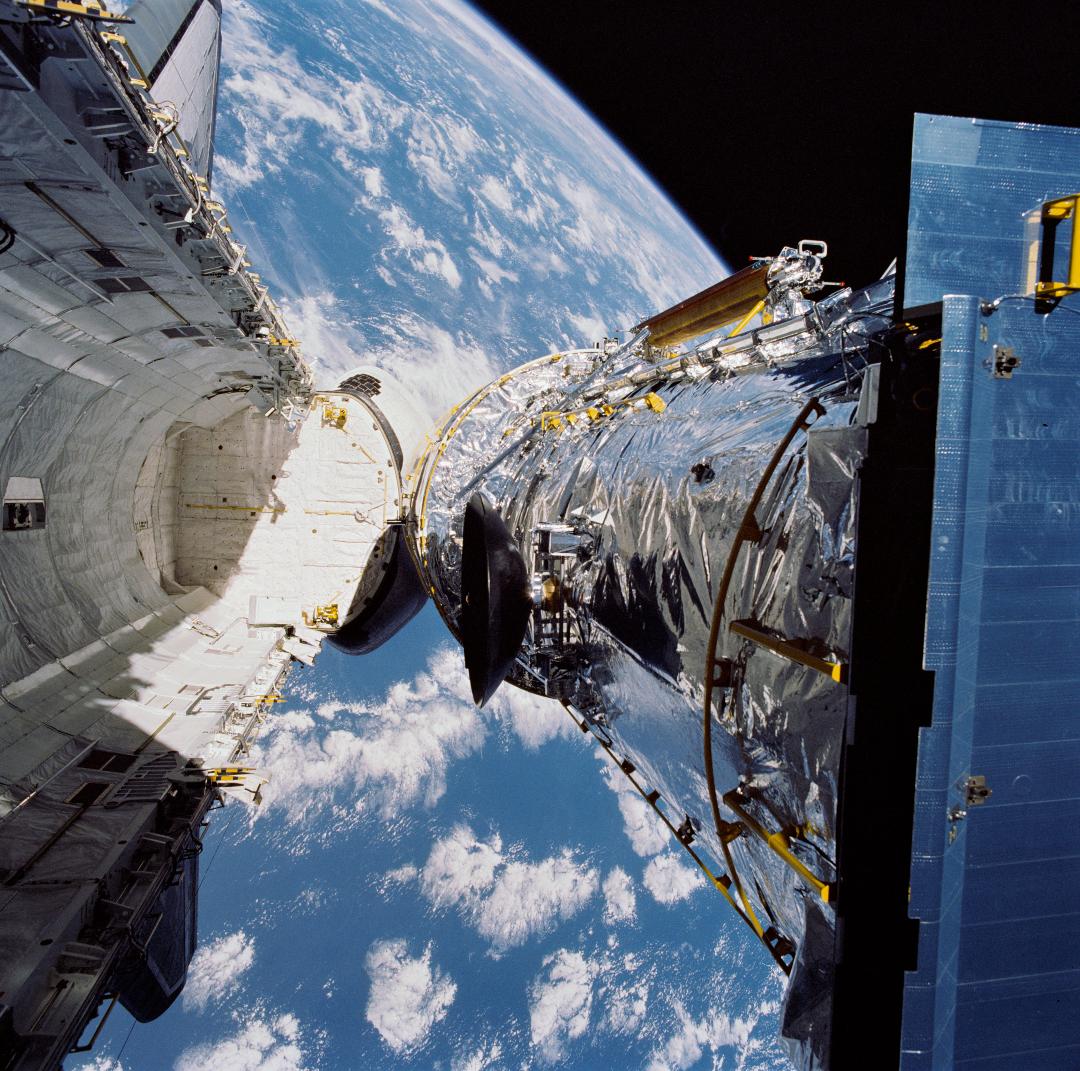 The Hubble Space Telescope is suspended above shuttle Discovery's cargo bay some 332 nautical miles above Earth