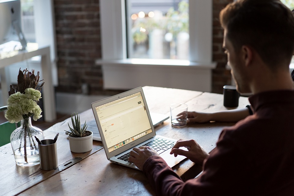 This is a picture of a man sitting down working at a laptop computer.