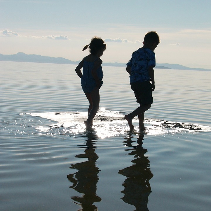 this is a picture of children walking through wet sand