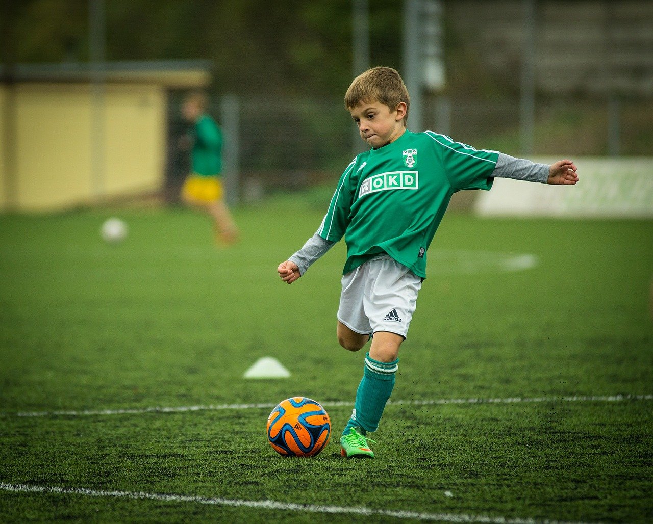 A young boy kicking a football.