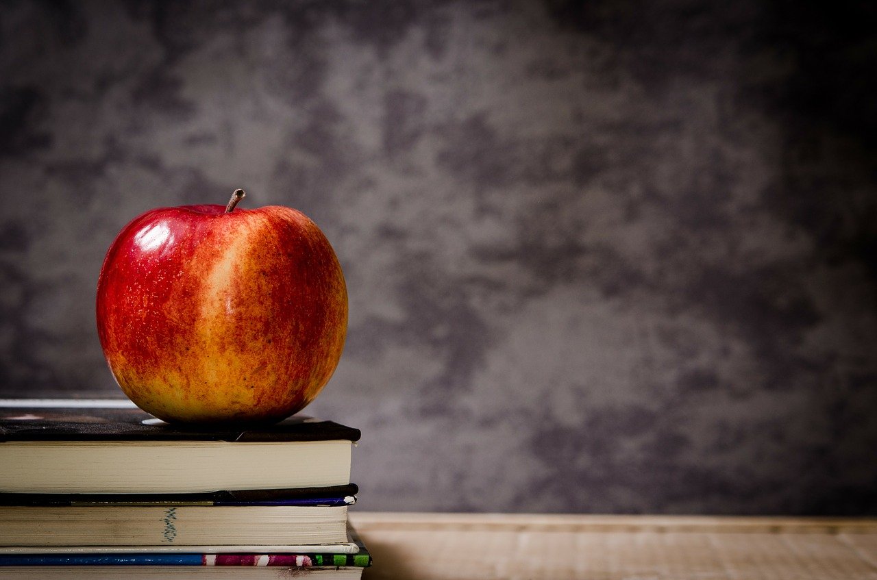 An apple sitting on a stack of books.