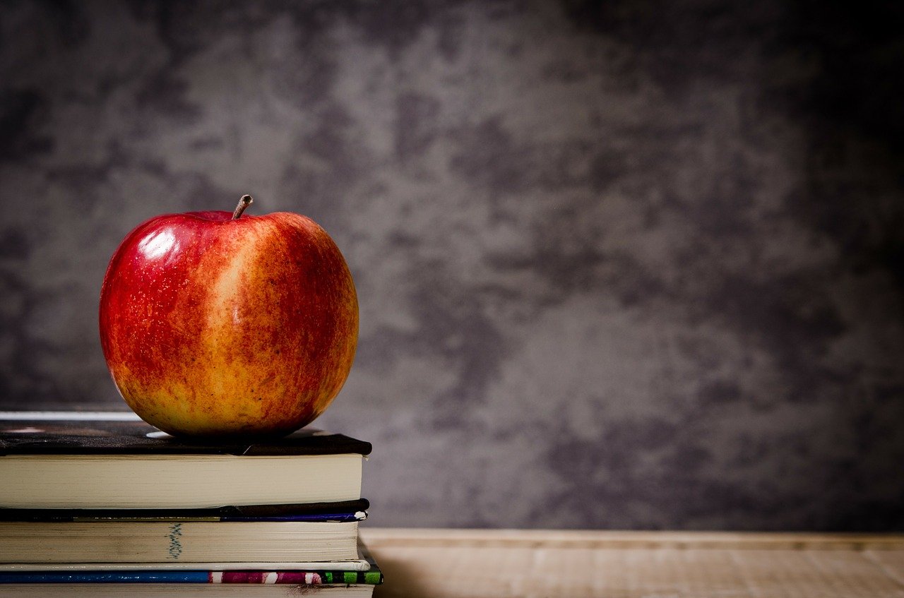 An apple sitting on a stack of books.