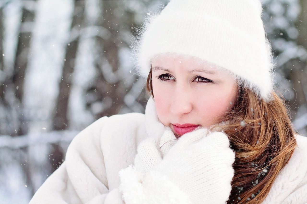 A woman wrapped up warmly in a snowy forest.