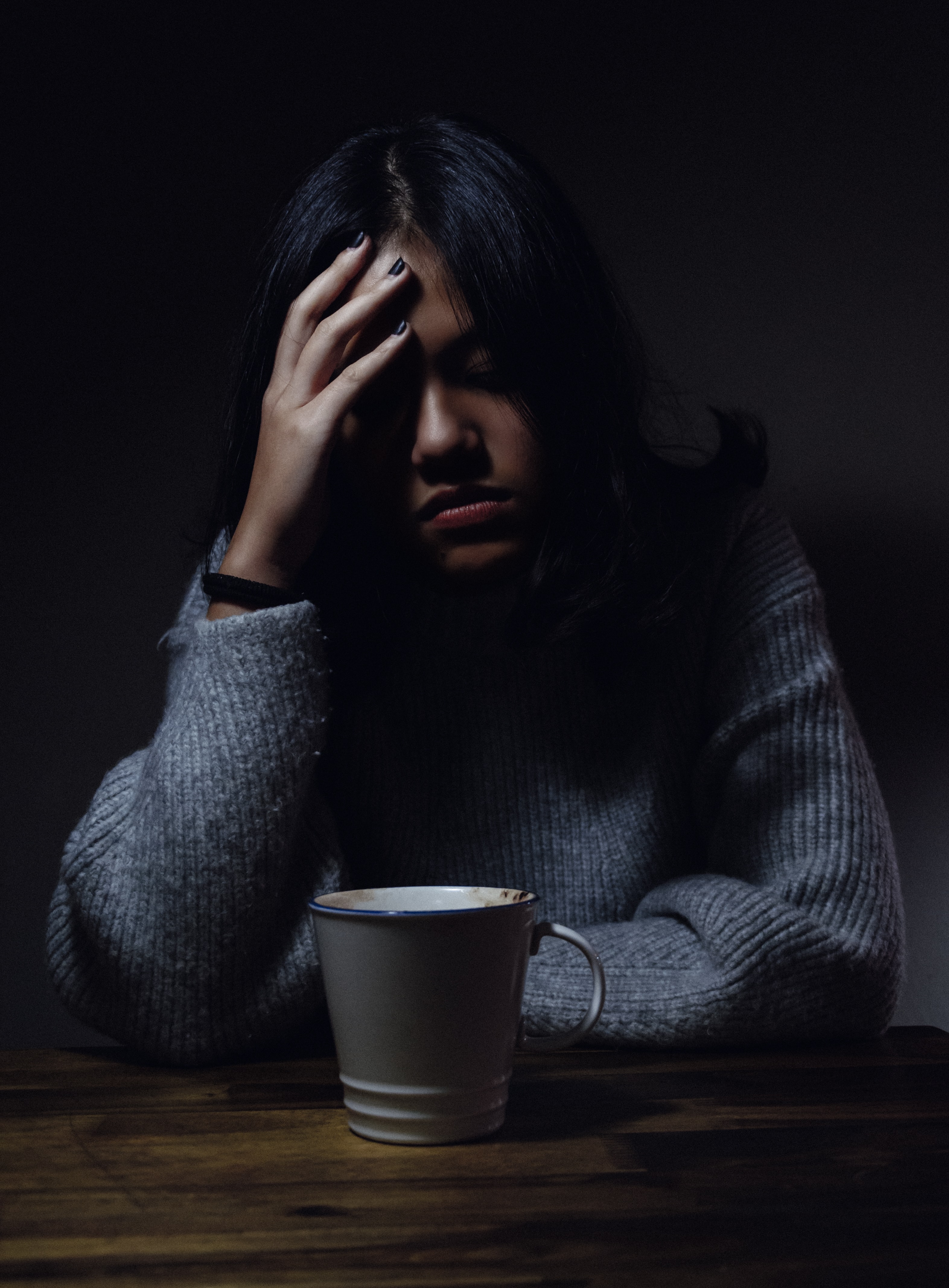 a woman sitting at table, in pain