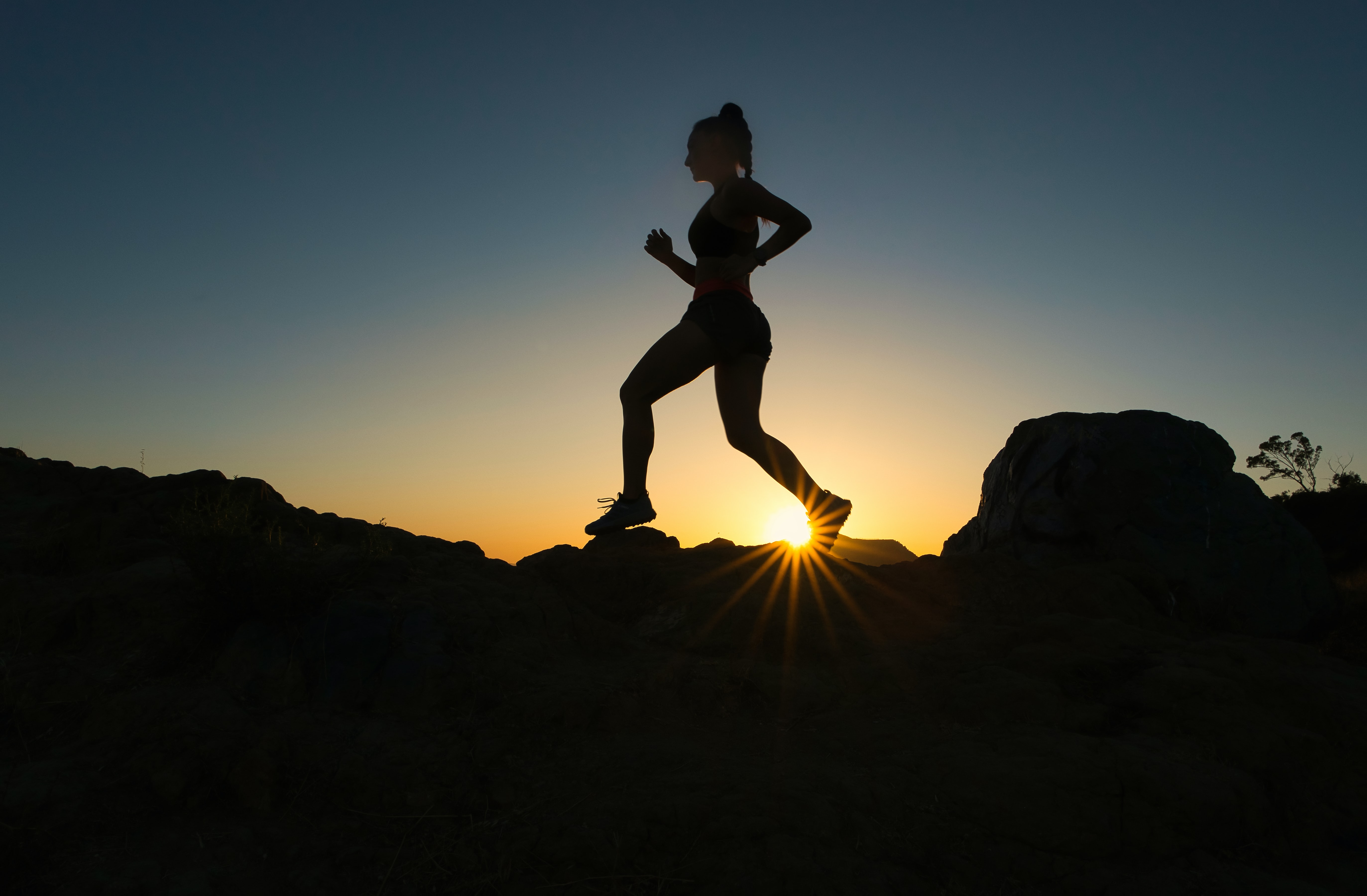 Silhouette of woman running over rocks