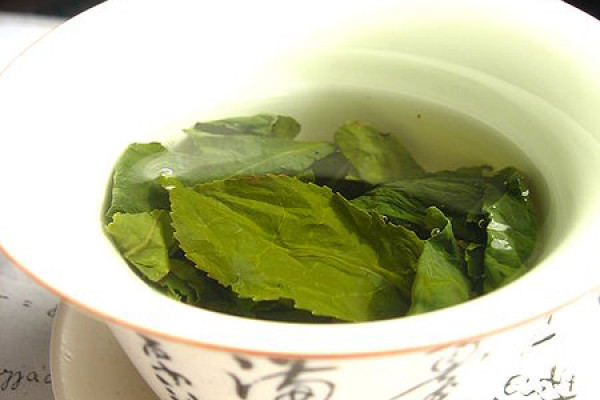 Green tea leaves steeping in an uncovered zhong (type of tea cup).