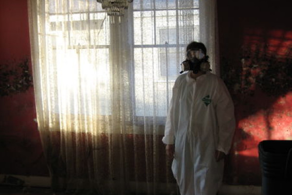 Man in hazard suit next to curtains