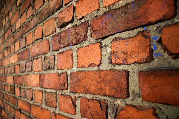 An old brick wall in English bond laid with alternating courses of headers and stretchers.