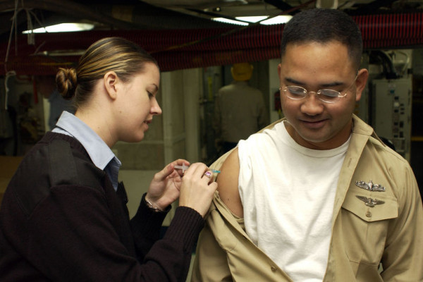 Hospital Corpsman 3rd Class Tiffany Long administers the influenza vaccination to a crew member aboard USS Kitty Hawk