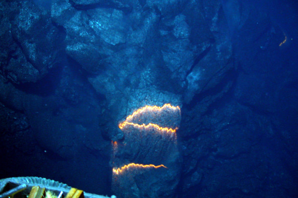  Bands of glowing magma, about 2,200 degrees Fahrenheit, are exposed as a pillow lava tube extrudes down slope from a submarine volcano. The image shows an approximately three-foot section across in an eruptive area spanning 100 yards and which runs...