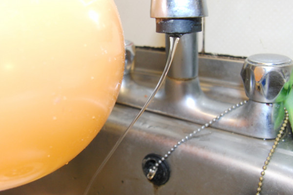 The charged balloon bends the stream of water