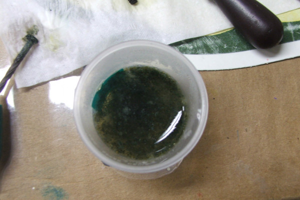 A container with an iron(II) hydroxide precipitate. It was made by electrolysis of a solution of sodium carbonate with an iron anode