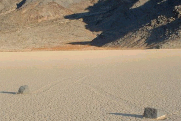 Picture of two rocks on Racetrack Playa in Death Valley. Notice the mysterious groves leading away from the stones.