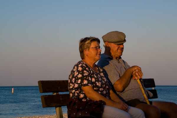 An elderly couple sitting together looking out to sea