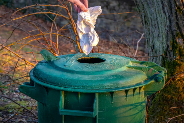 Throwing away a paper towel in a bin.