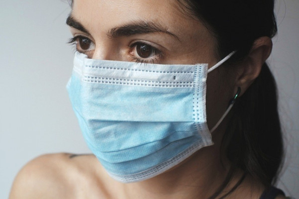 A woman wearing a blue facemask.