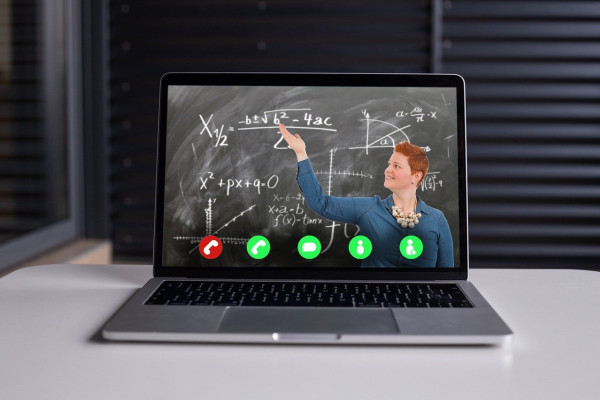 image of teacher next to blackboard, via video call