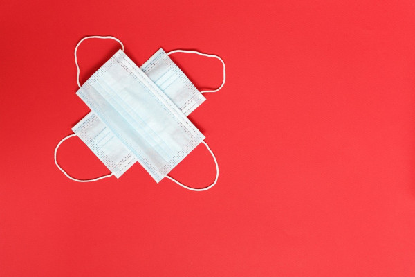 Two facemasks crossed on a red background.