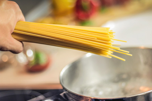 Spaghetti being added to a pot