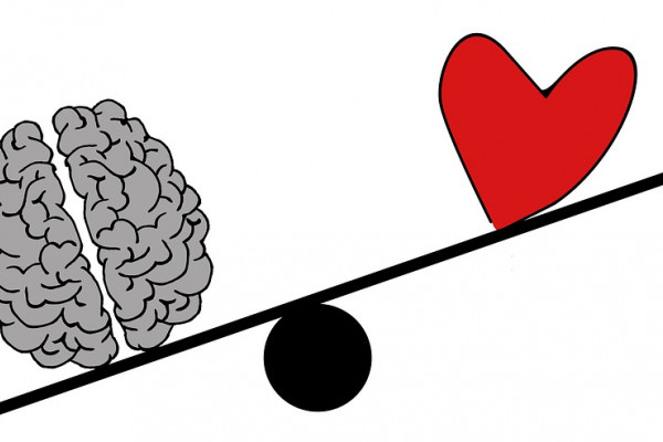 A cartoon brain outweighing a cartoon heart on a balance scale.