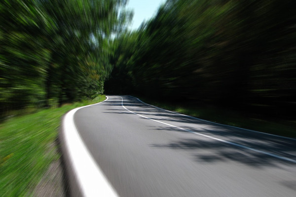 A photo taken from on the road while the trees blur due to speed