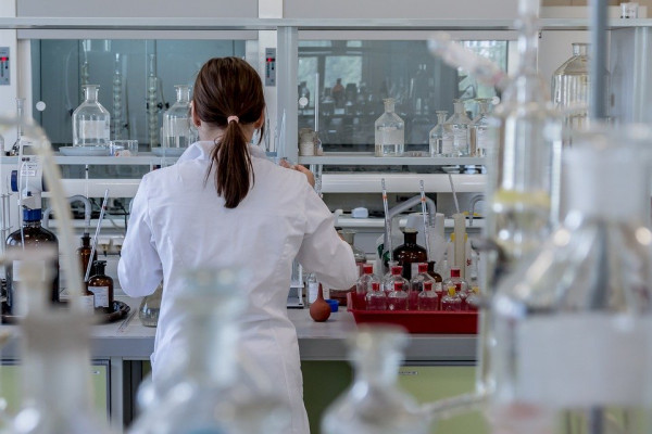 A woman with her back to the camera in a lab, using scientific equipment