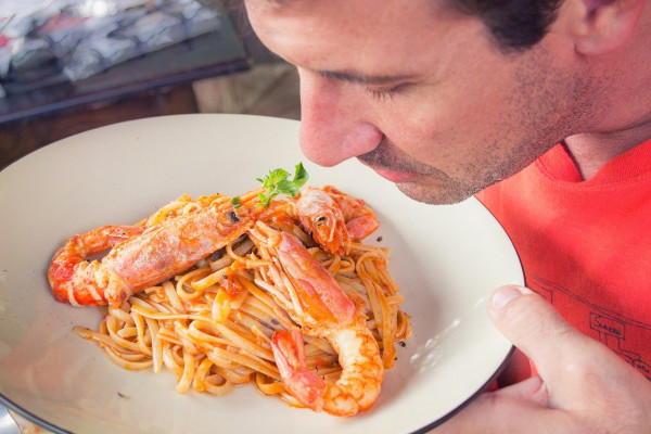 photo of a man smelling some pasta