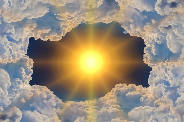 The sun shining through a stylised hole in some clouds.
