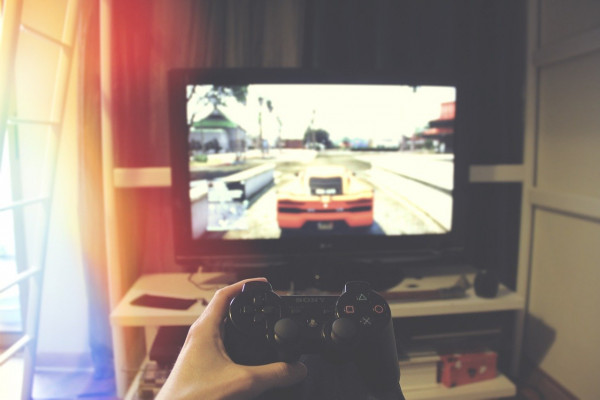 A person holding a controller in front of a TV, playing a car racing game