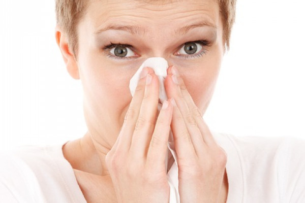 Woman holding a tissue to her nose.