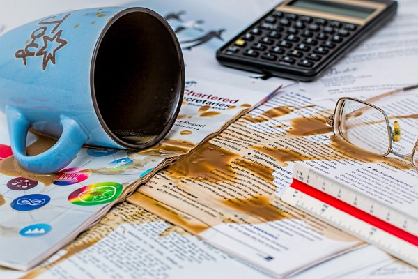 A mug of tea or coffee spilled over some papers.