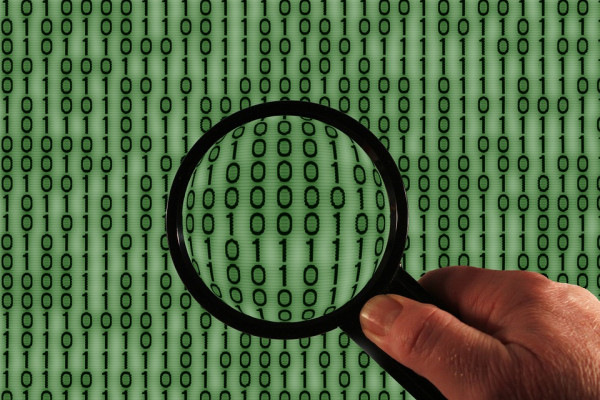 A magnifying glass in front of binary code.