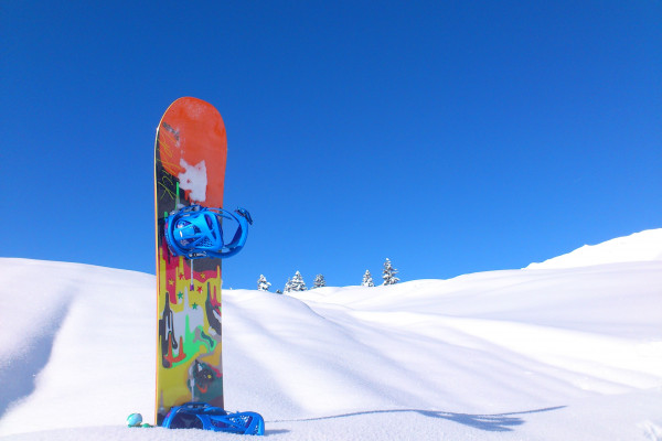 A snowboard stuck halfway into some snow.