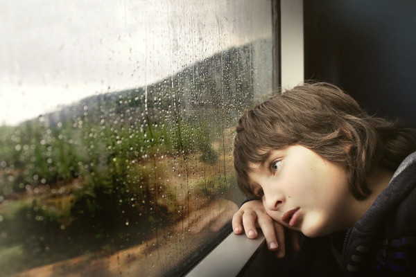 CHILD LEANING ON THE WINDOWSILL LOOKING BORED