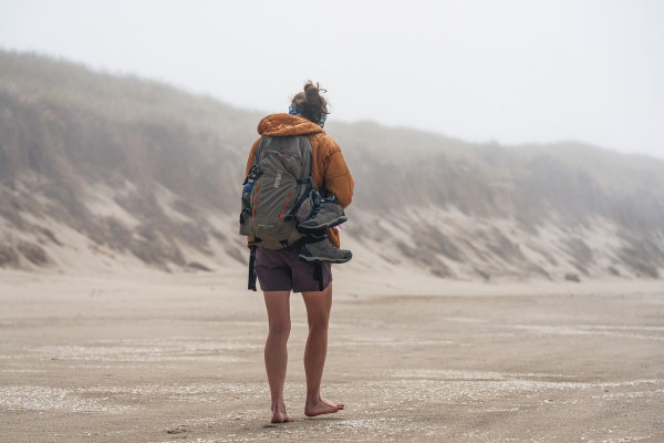A woman with a rucksack walking on a beach
