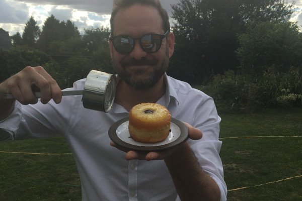 photo of chef Tristan Welch displaying a cake cooked on a BBQ
