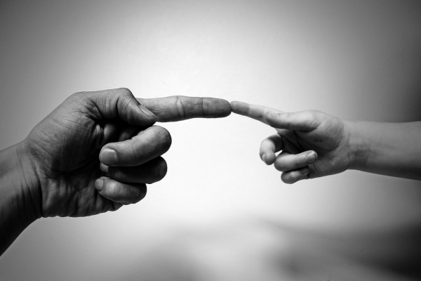 Adult finger touching a child's finger, based on Michelangelo's painting