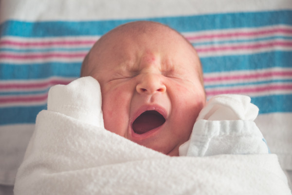 Yawning baby wrapped in cloth