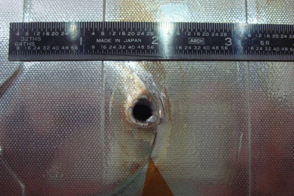  Image of the entry hole created on Space Shuttle Endeavour's radiator panel by the impact of unknown space debris.