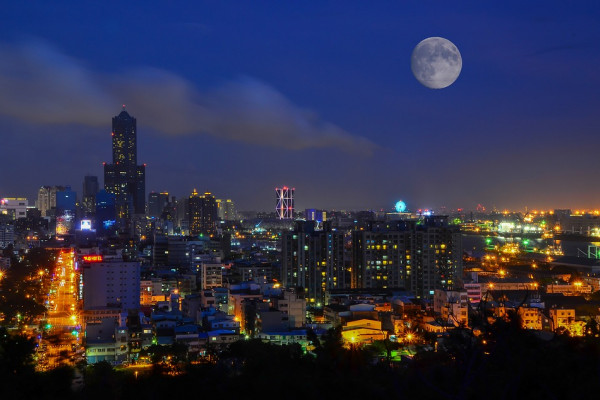 A moon rising over a cityscape
