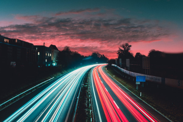 A road at sunset, with the lights from cars travelling up and down